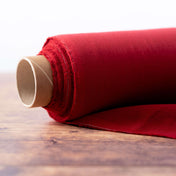Roll of berry red linen fabric on wooden table