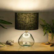 Dark green lampshade made from textured linen illuminated on recycled glass table lamp