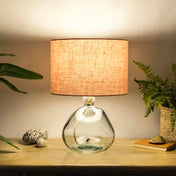 Blush pink lampshade made from textured linen illuminated on recycled glass table lamp