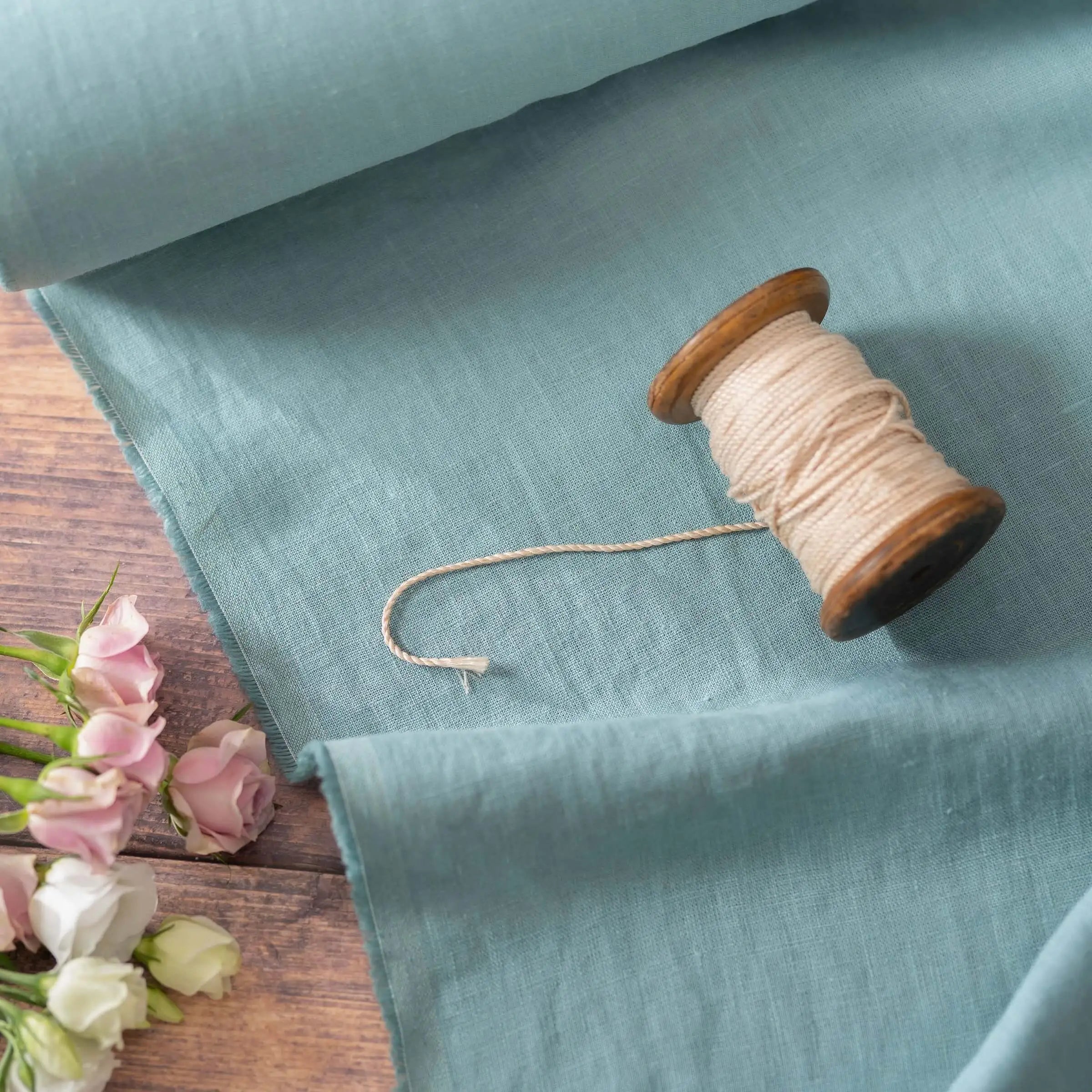 Dusty Turquoise linen fabric, ready to cut, with scissors, thread bobbins and flowers