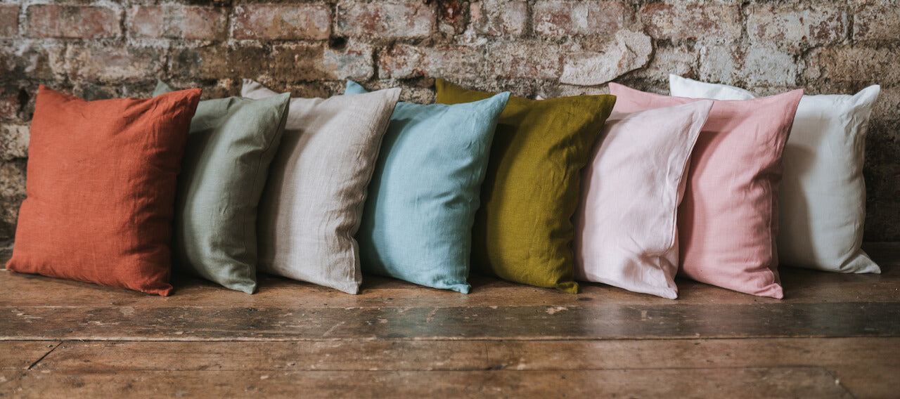 colourful washed linen cushions in a row in wooden floor