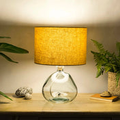 Mustard yellow lampshade made from textured linen illuminated on recycled glass table lamp