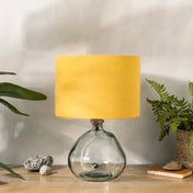 Honey yellow linen lampshade with recycled glass base on wooden desk with plants