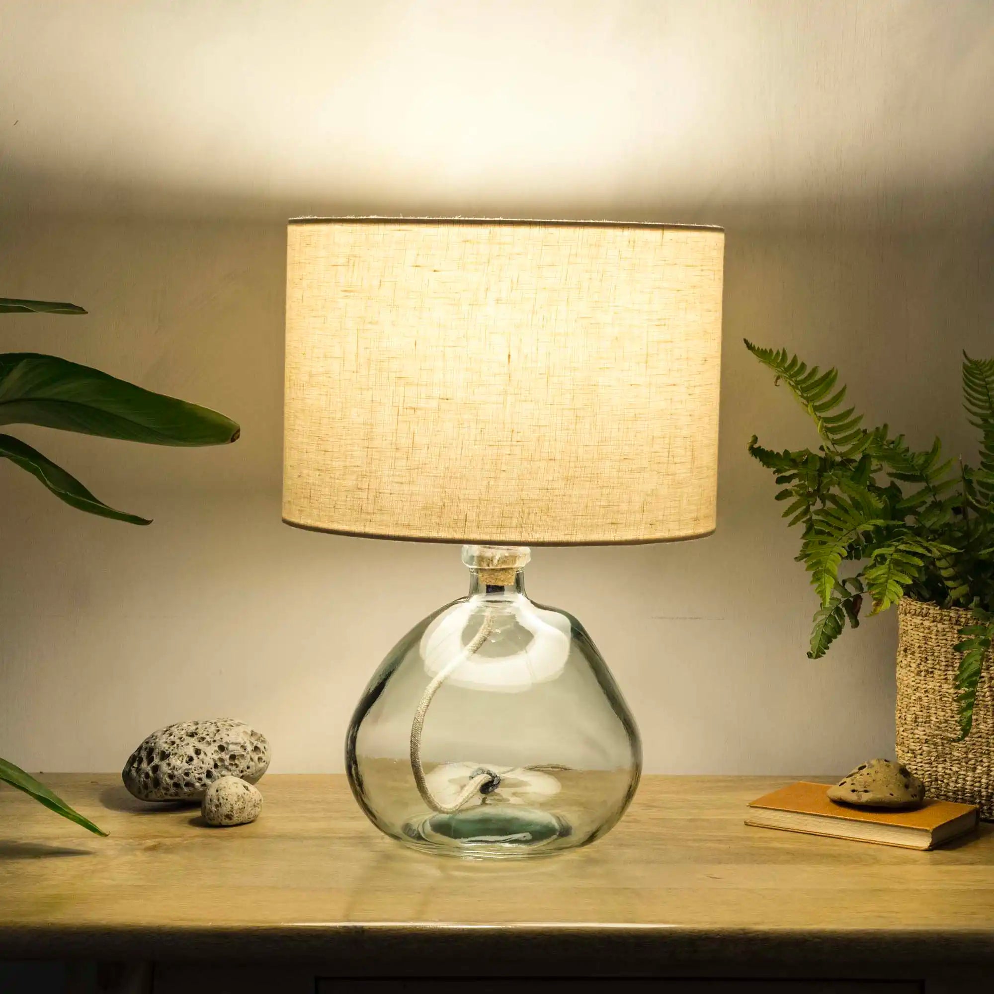 Cream lampshade made from textured linen illuminated on recycled glass table lamp