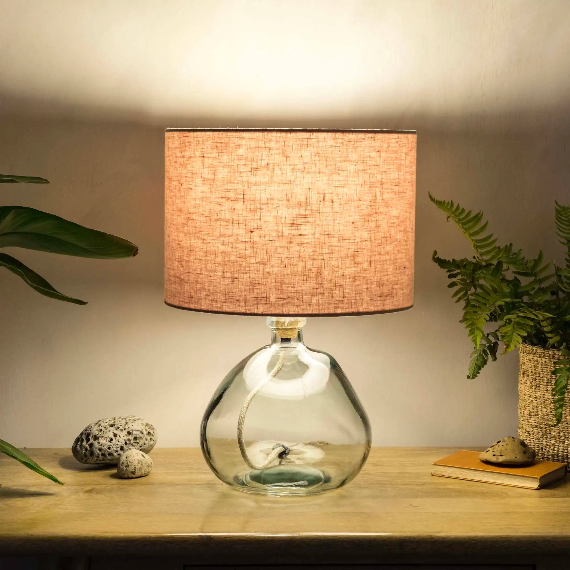 Dusty pink lampshade made from textured linen illuminated on recycled glass table lamp