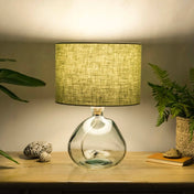 Light sage lampshade made from textured linen illuminated on recycled glass table lamp