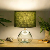 Moss green lampshade made from textured linen illuminated on recycled glass table lamp