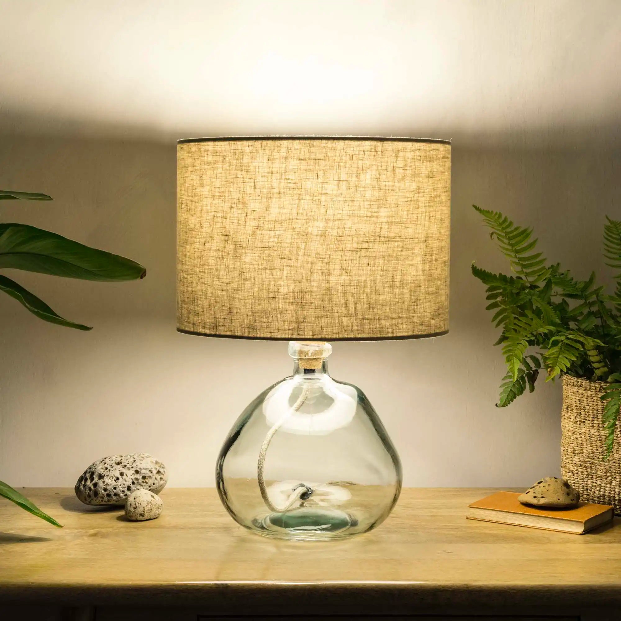 Natural linen lampshade illuminated on recycled glass table lamp