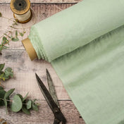 Pistachio Green linen fabric, ready to cut, with scissors, thread bobbins and eucalyptus 