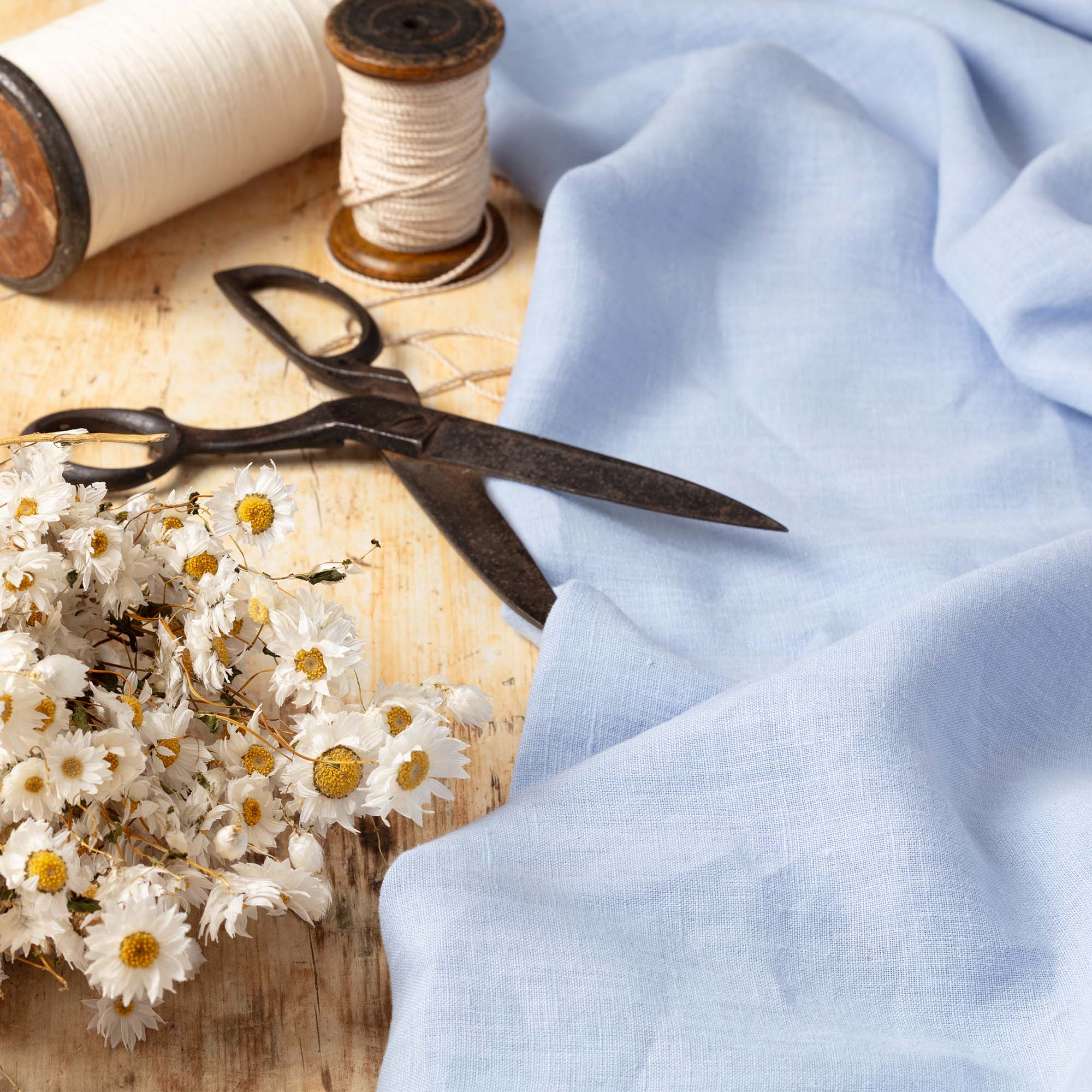 Powder Blue linen fabric, ready to cut, with scissors, thread bobbins and flowers
