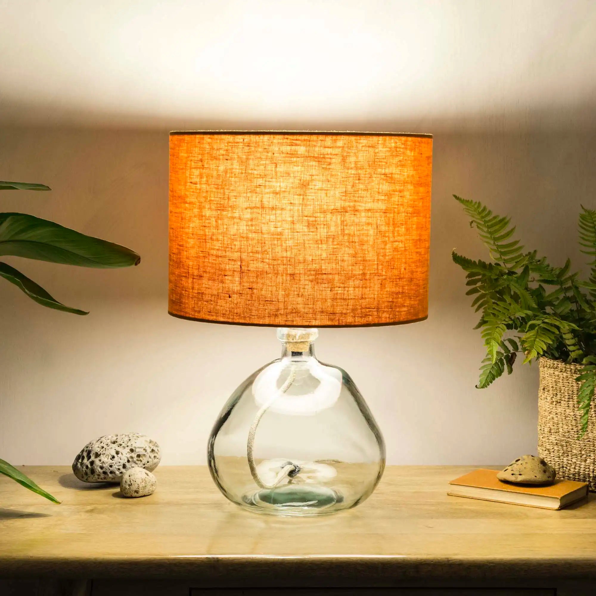 Pumpkin orange lampshade made from textured linen illuminated on recycled glass table lamp