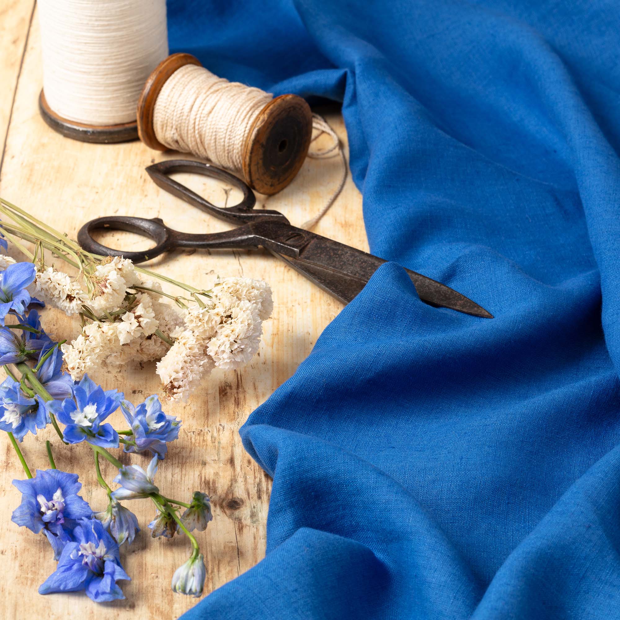 Sapphire Blue linen fabric, ready to cut, with scissors, thread bobbins and flowers