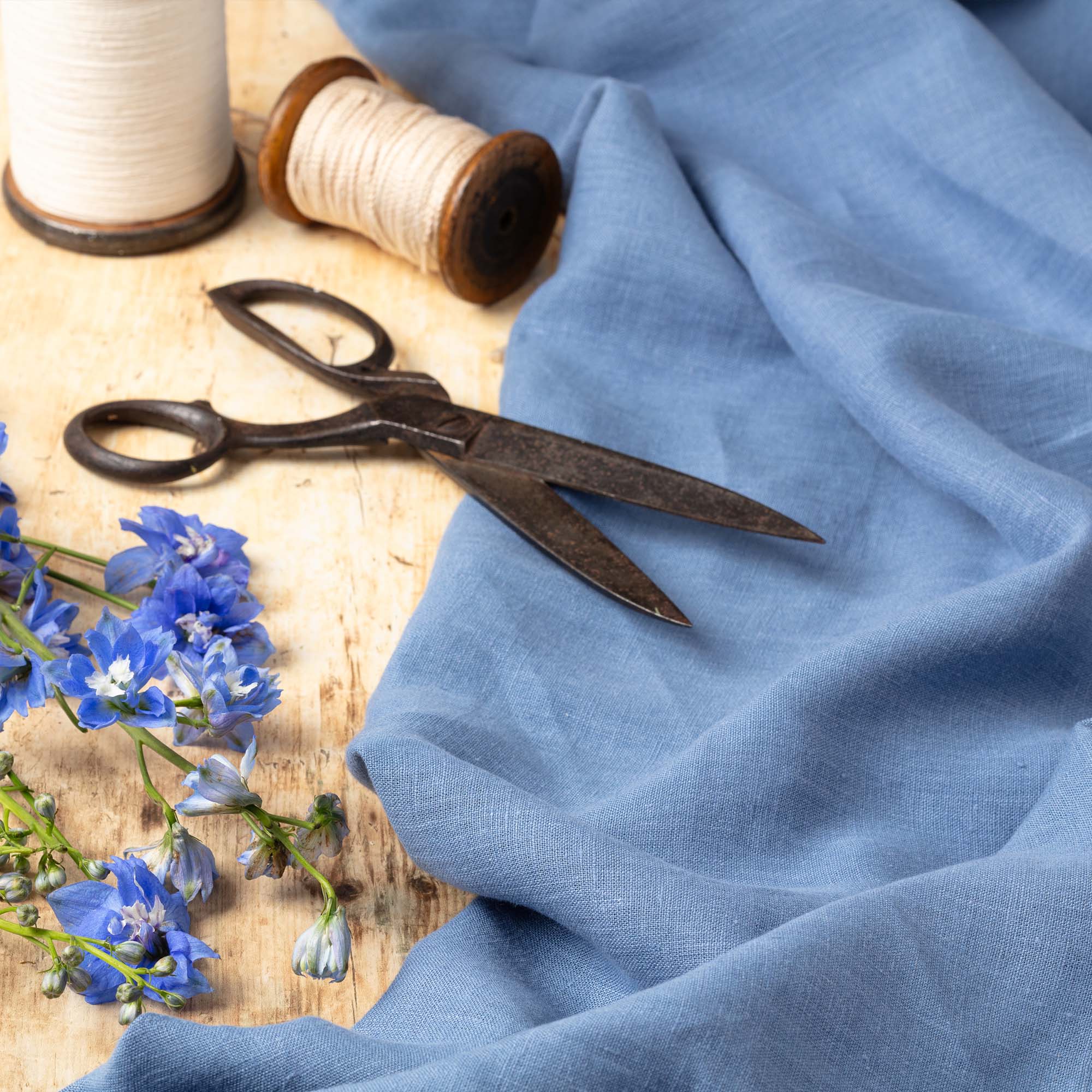 Steel Blue linen fabric, ready to cut, with scissors, thread bobbins and flowers