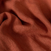 Terracotta linen fabric, folded to show its soft, natural texture