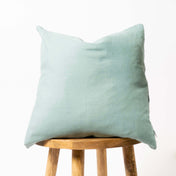 Dusty turquoise linen cushion cover on wooden stool