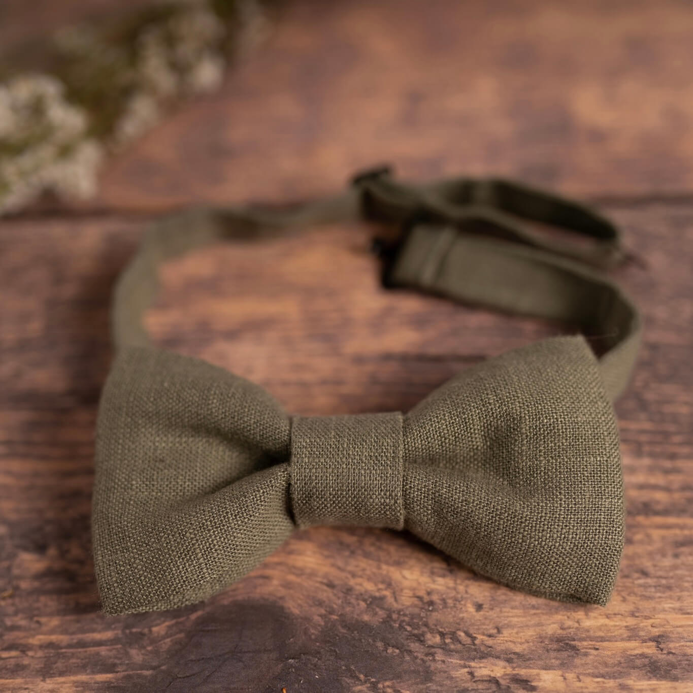 Dusty sage green linen bow tie on wooden table
