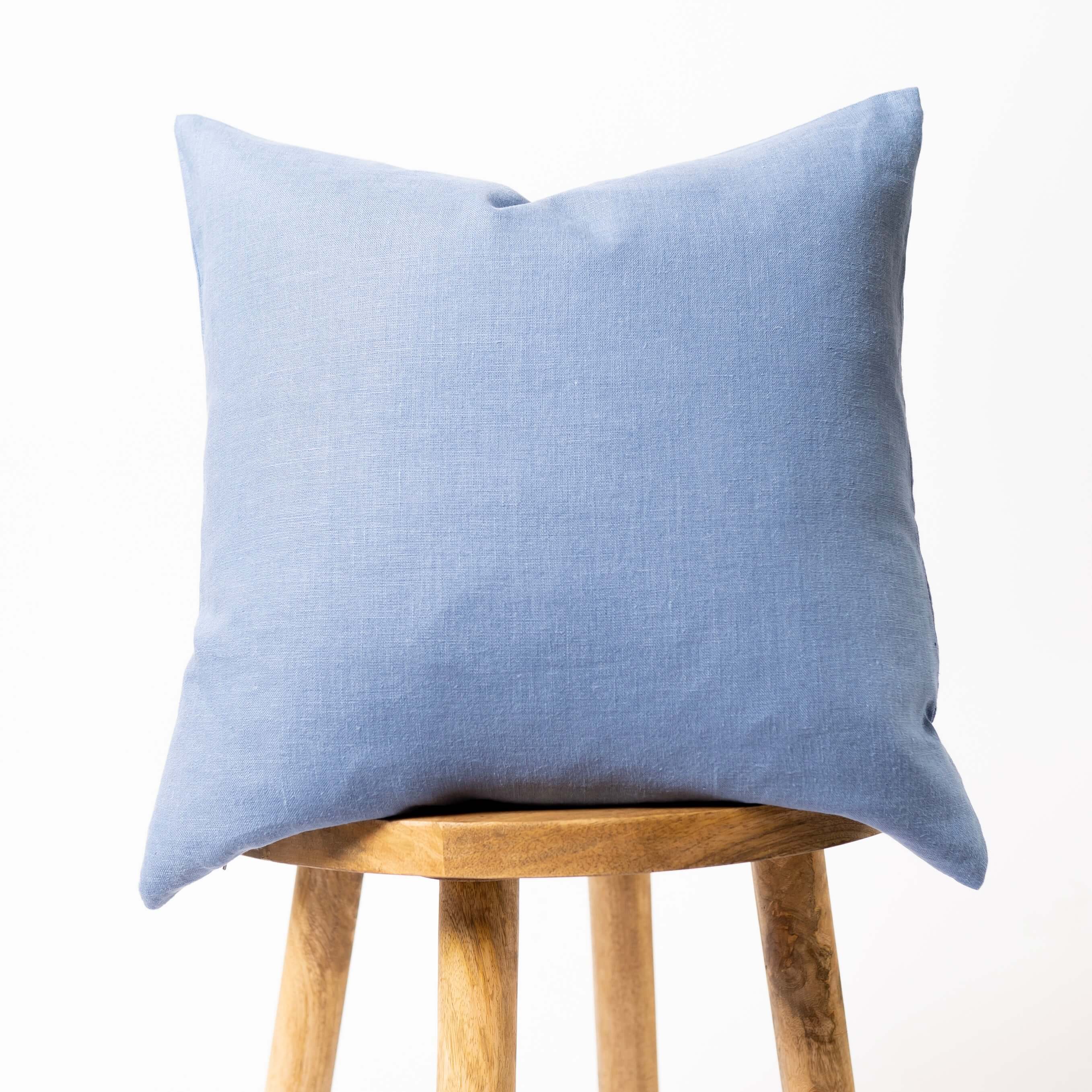 Dusty blue linen cushion cover on wooden stool