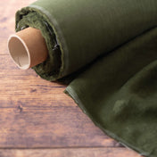 Roll of avocado green linen fabric on wooden table