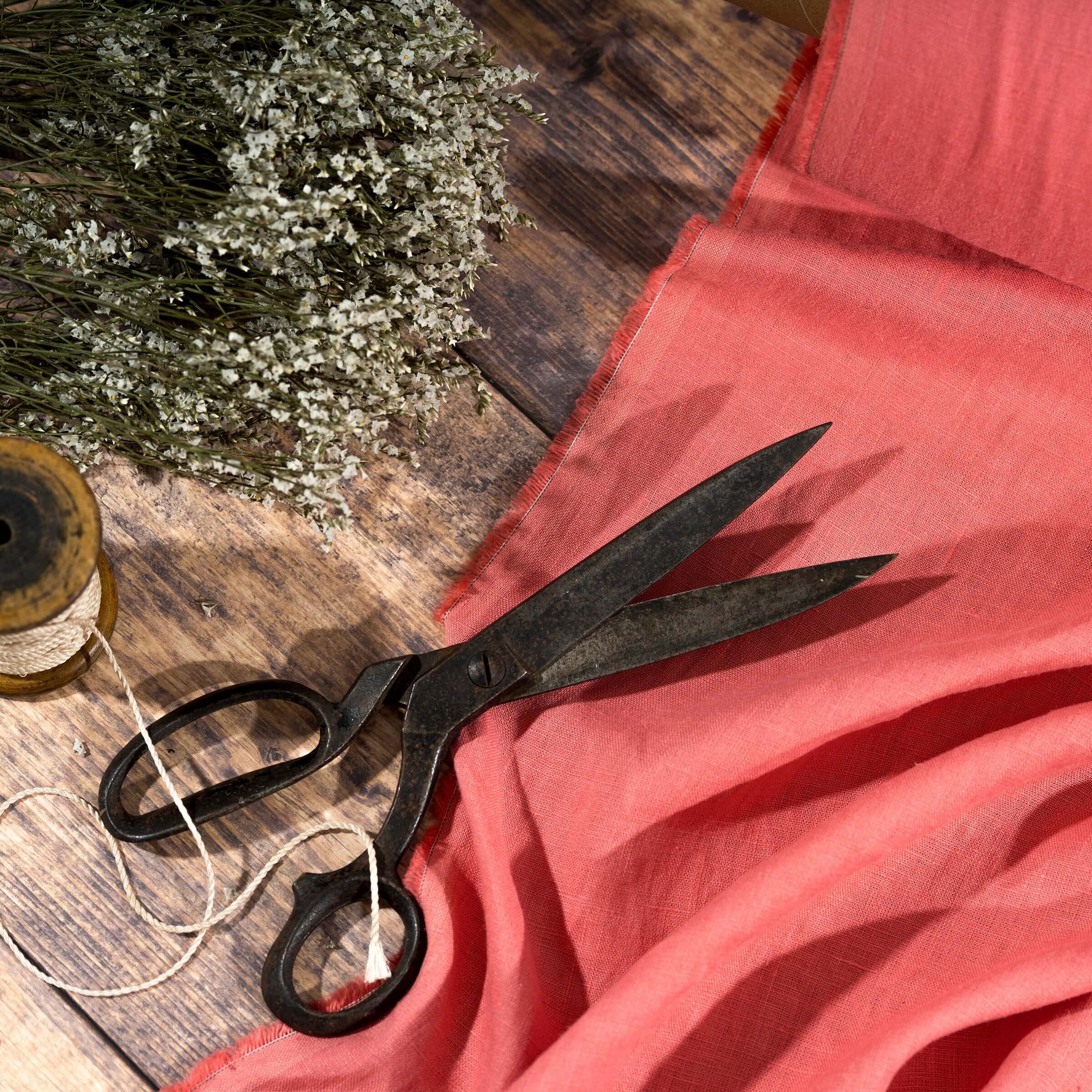 Coral Pink linen fabric, ready to cut, with scissors, thread bobbins and flowers