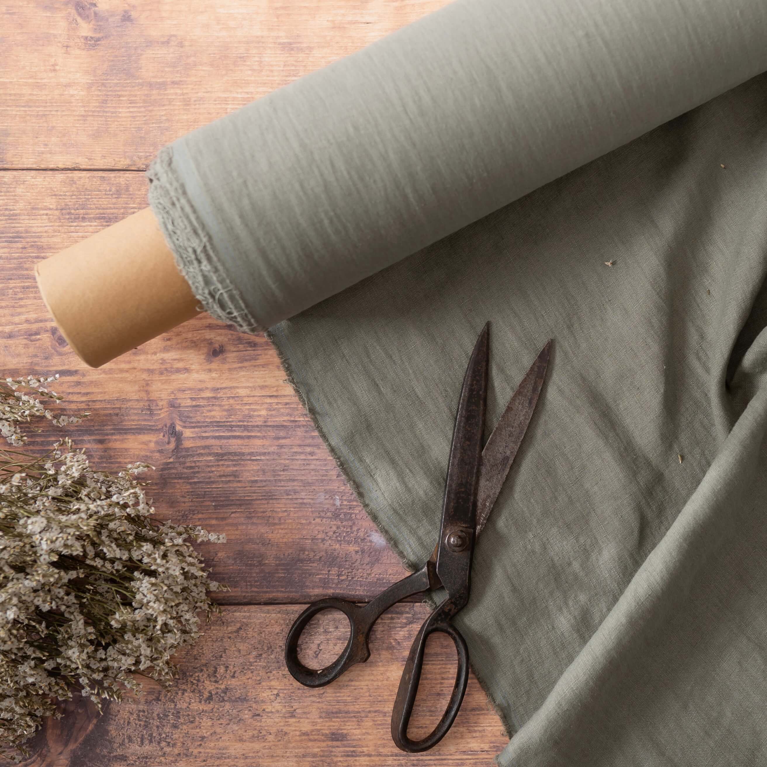 Dusty Sage Green linen fabric, ready to cut, with scissors, thread bobbins and flowers