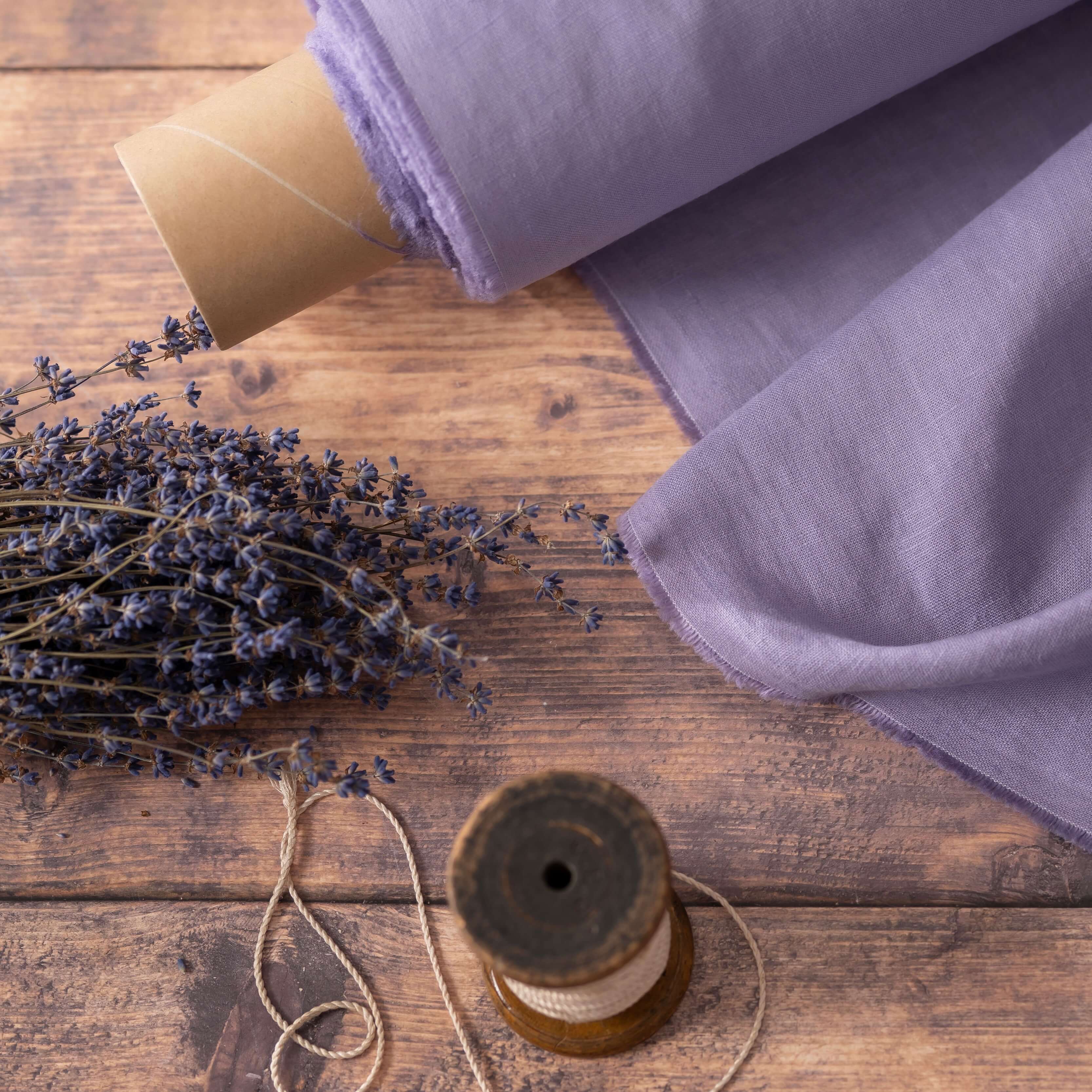 Lavender linen fabric, ready to cut, with thread bobbins and dried lavender