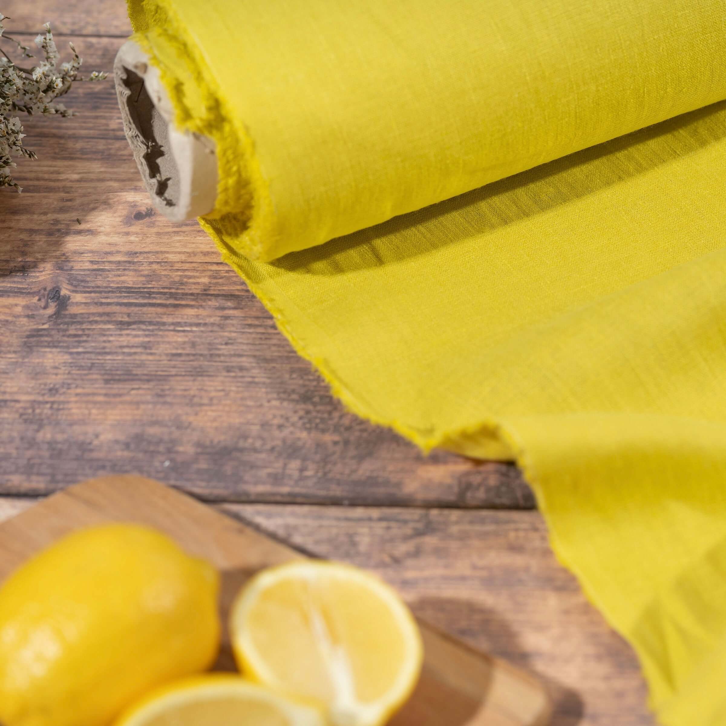 Lemon linen fabric on wooden table, ready to cut, with lemons