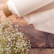 Light Cream linen fabric on wooden table, ready to cut with dried flowers