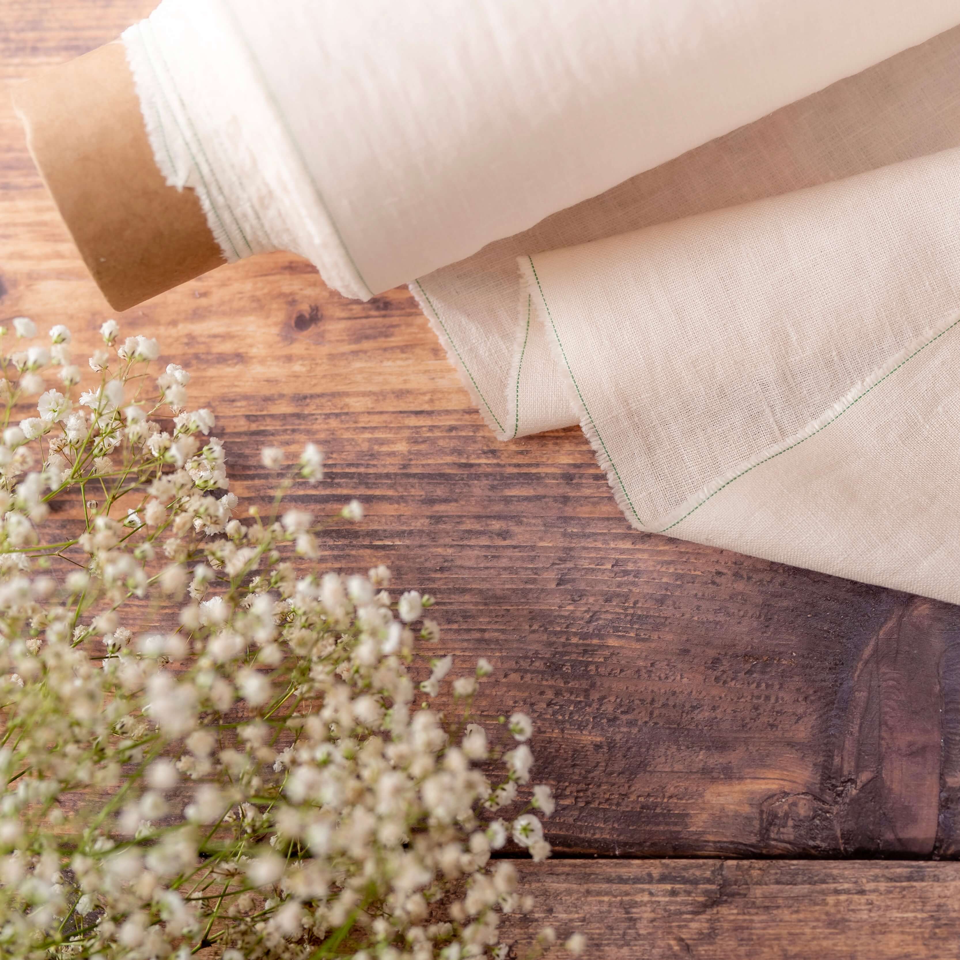 Light Cream linen fabric on wooden table, ready to cut with dried flowers