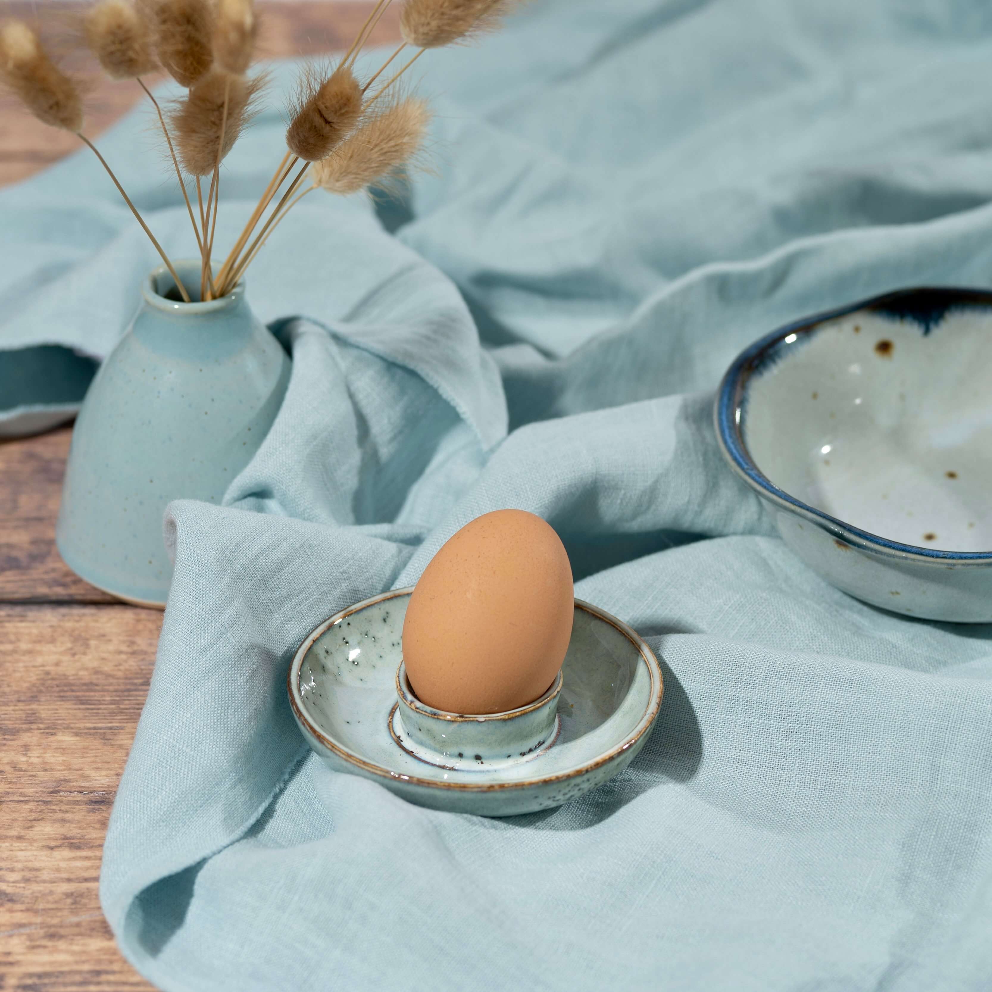 Light Duck Egg Blue linen fabric on wooden-table, with blue pottery
