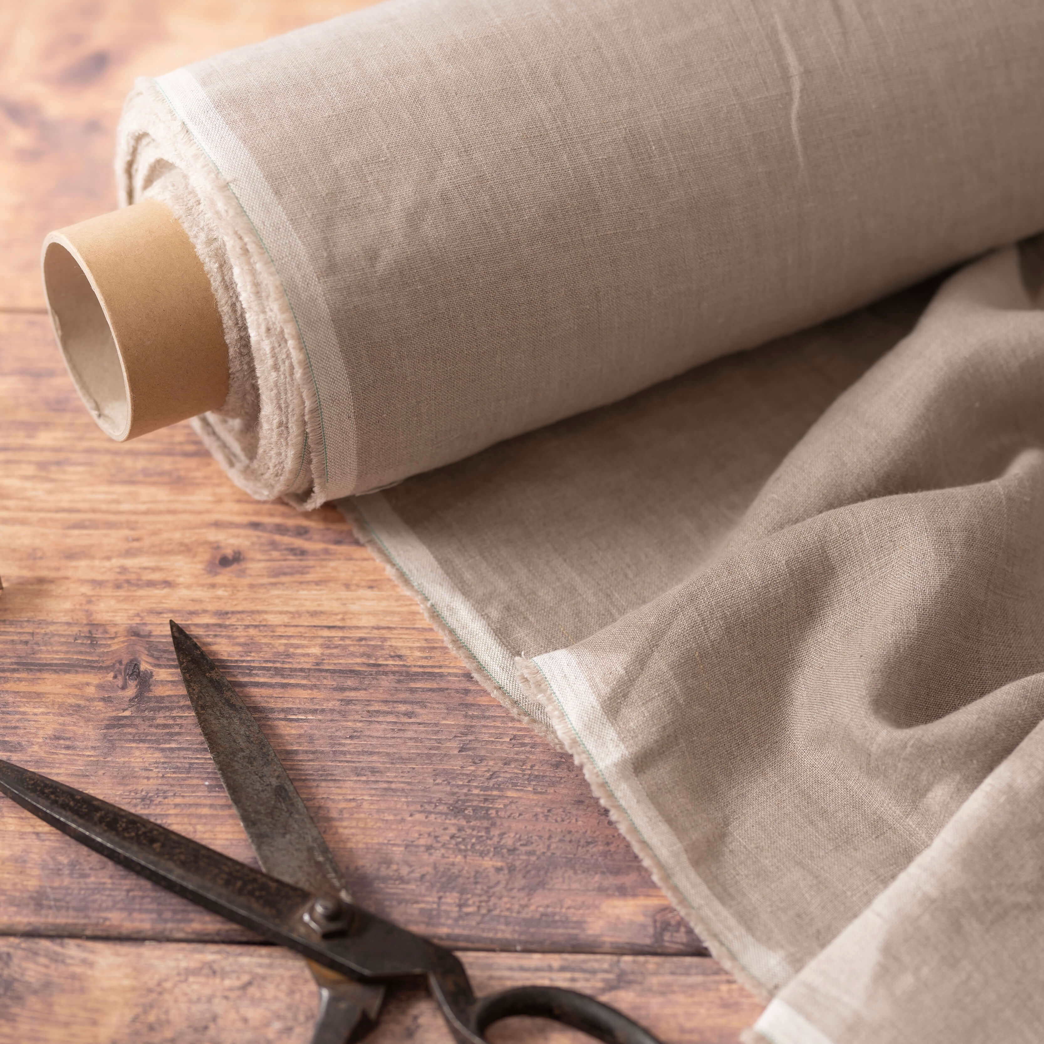 Natural linen fabric on wooden table, ready to cut, with scissors