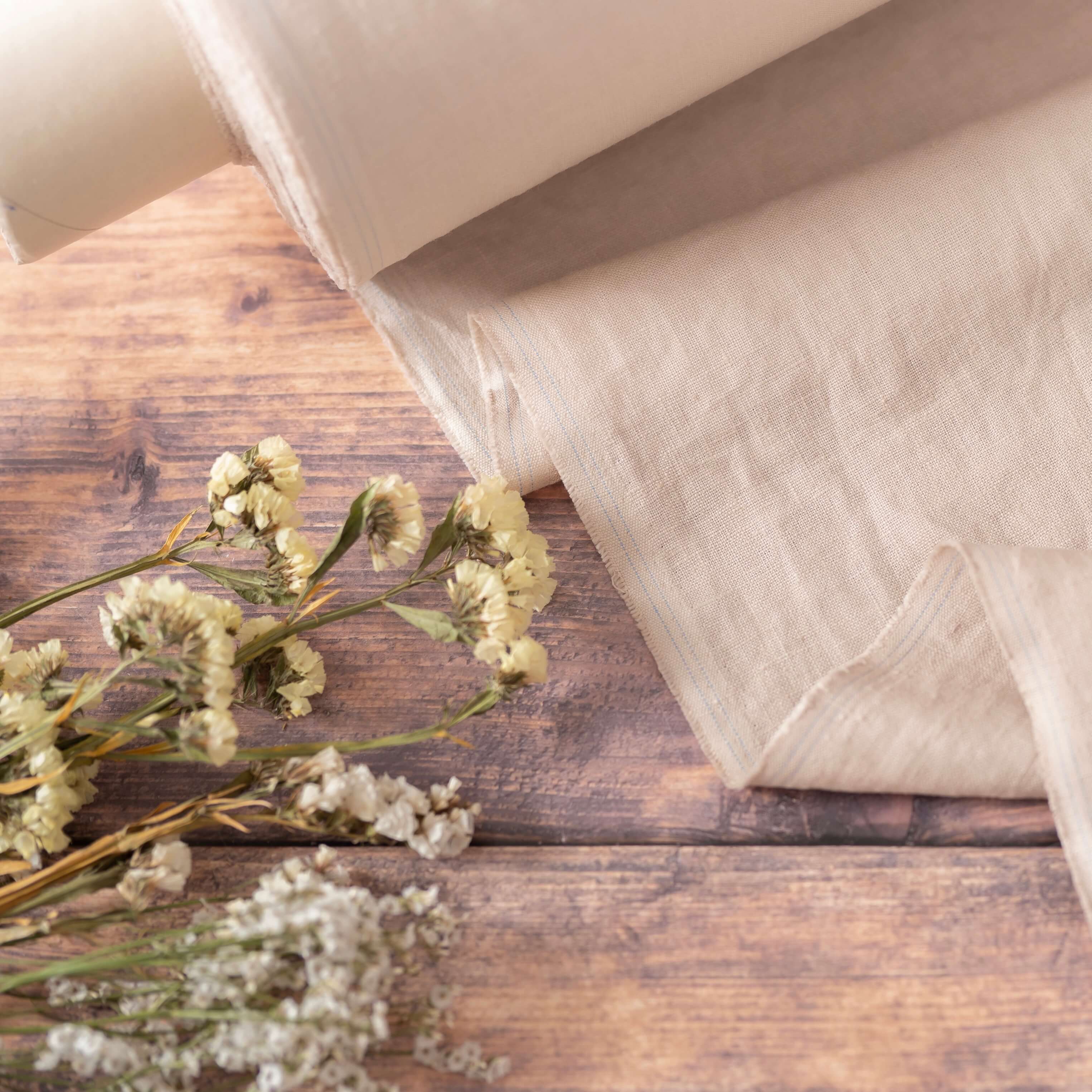 Oatmeal linen fabric, ready to cut, with scissors, thread bobbins and flowers
