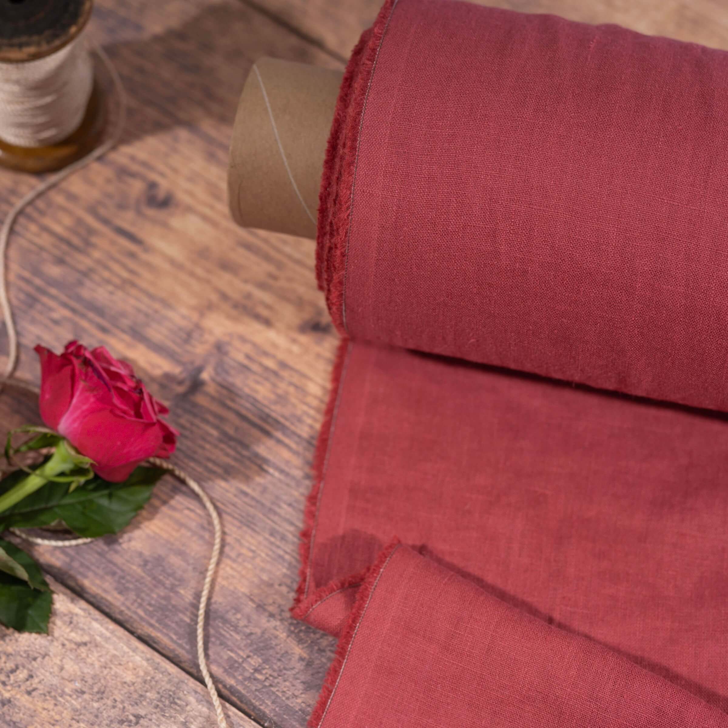 Raspberry linen fabric, ready to cut, with scissors, thread bobbins and flowers