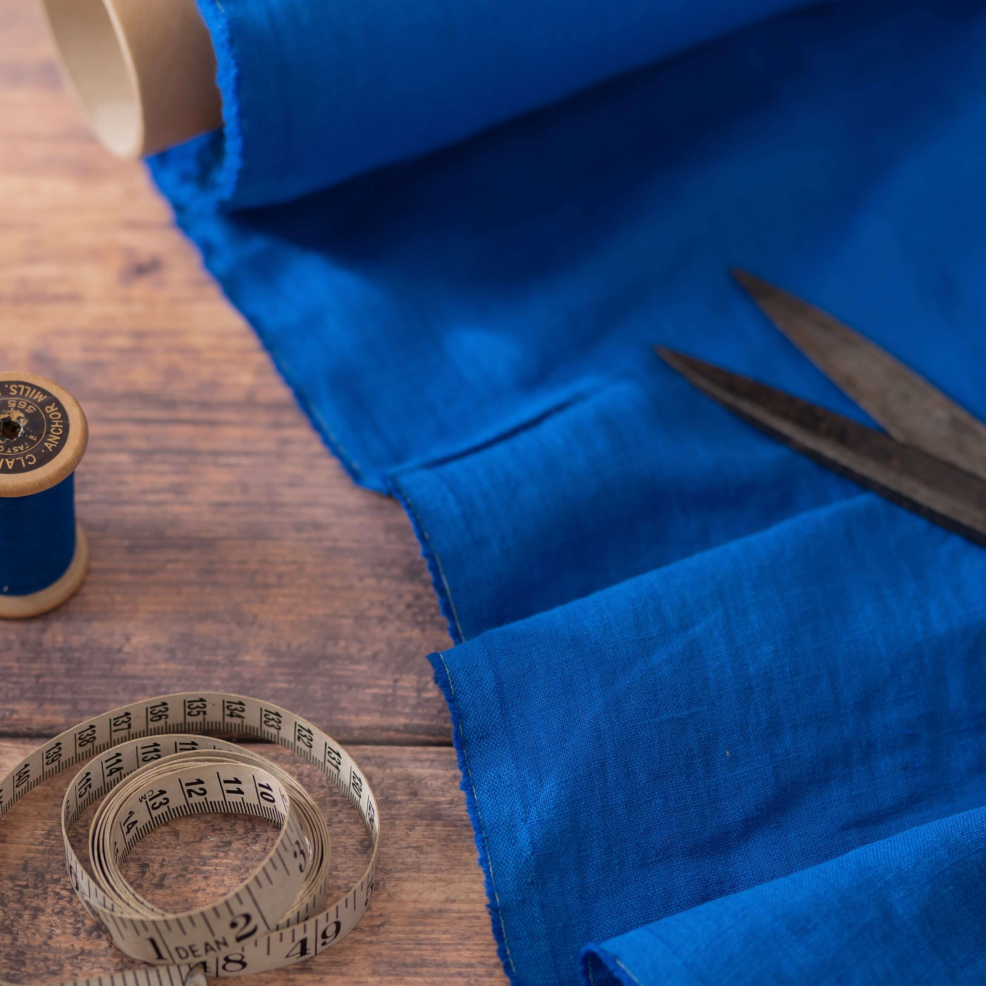 Royal Blue linen fabric, ready to cut, with measuring tape and thread bobbins 