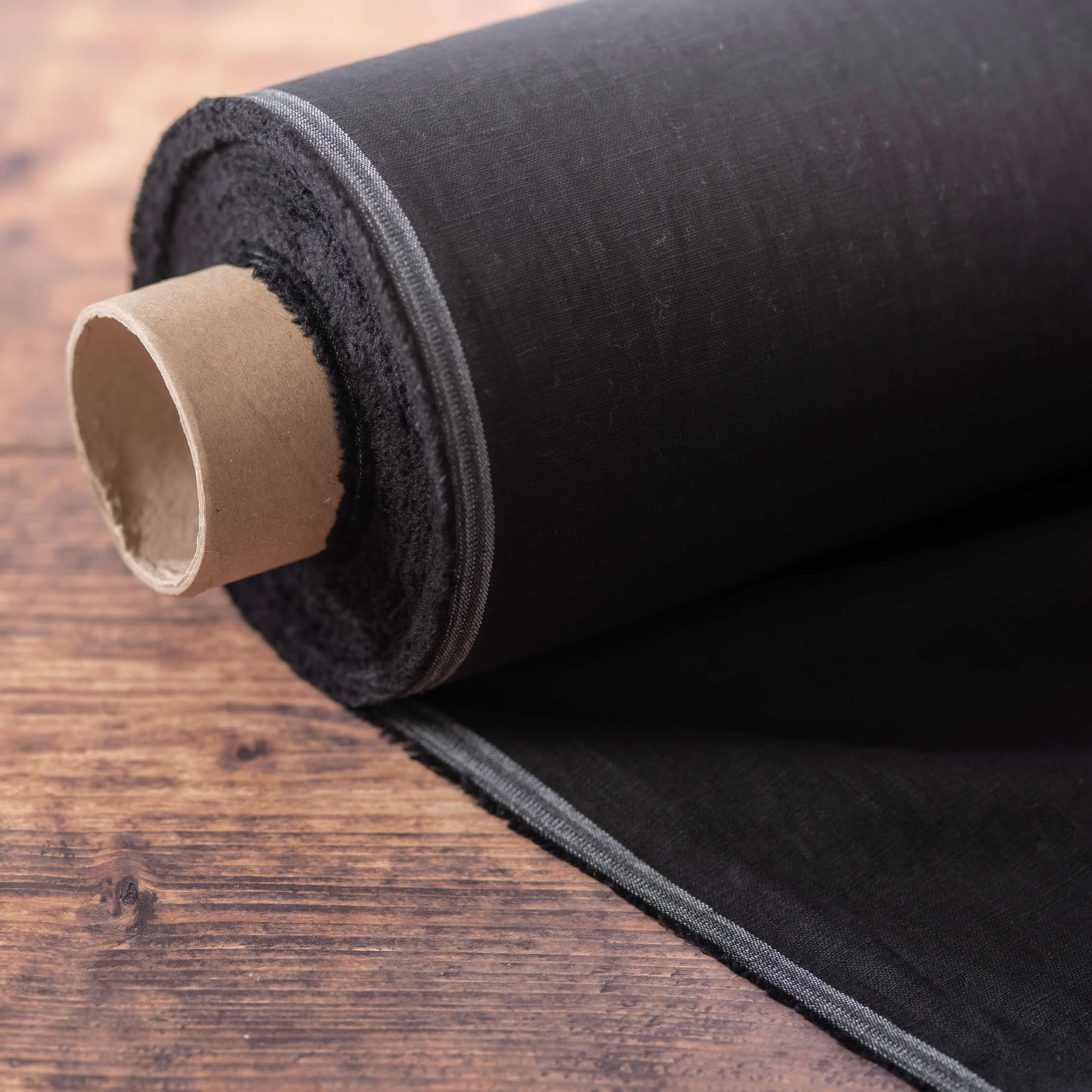 Roll of black linen fabric on wooden table