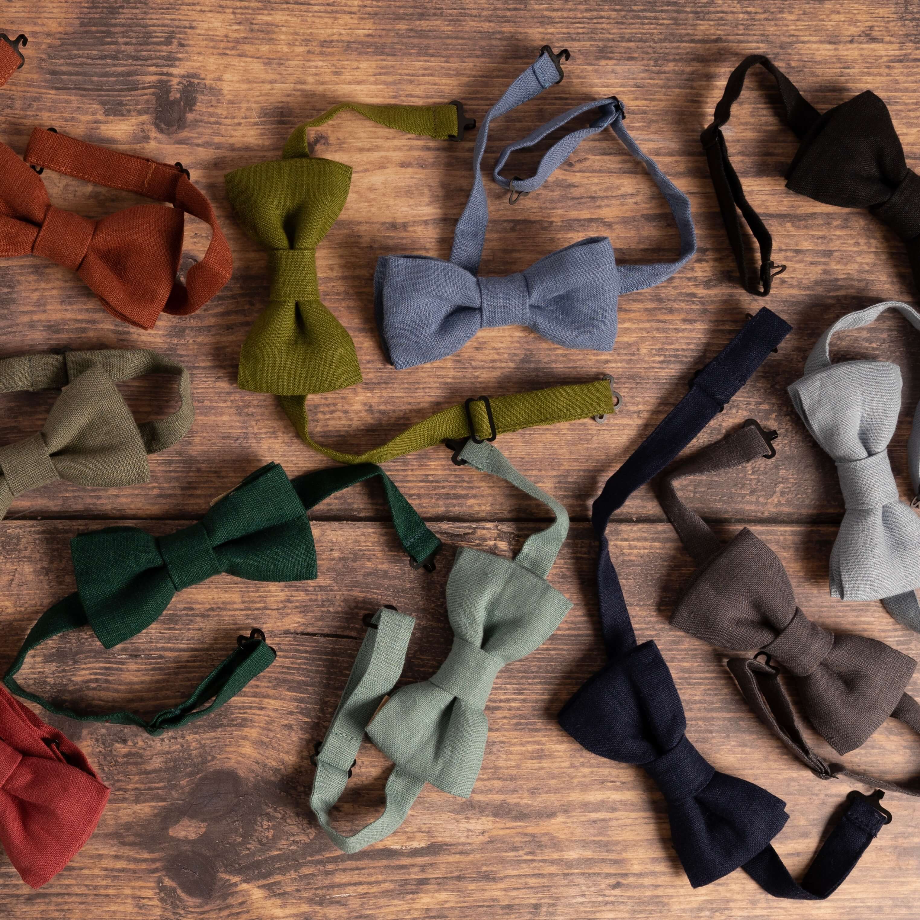 Selection of coloured linen bow ties on wooden table