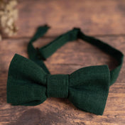 Close up of dark forest green bow tie on wooden table