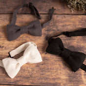 Selection of black, grey and white linen bow ties on wooden table