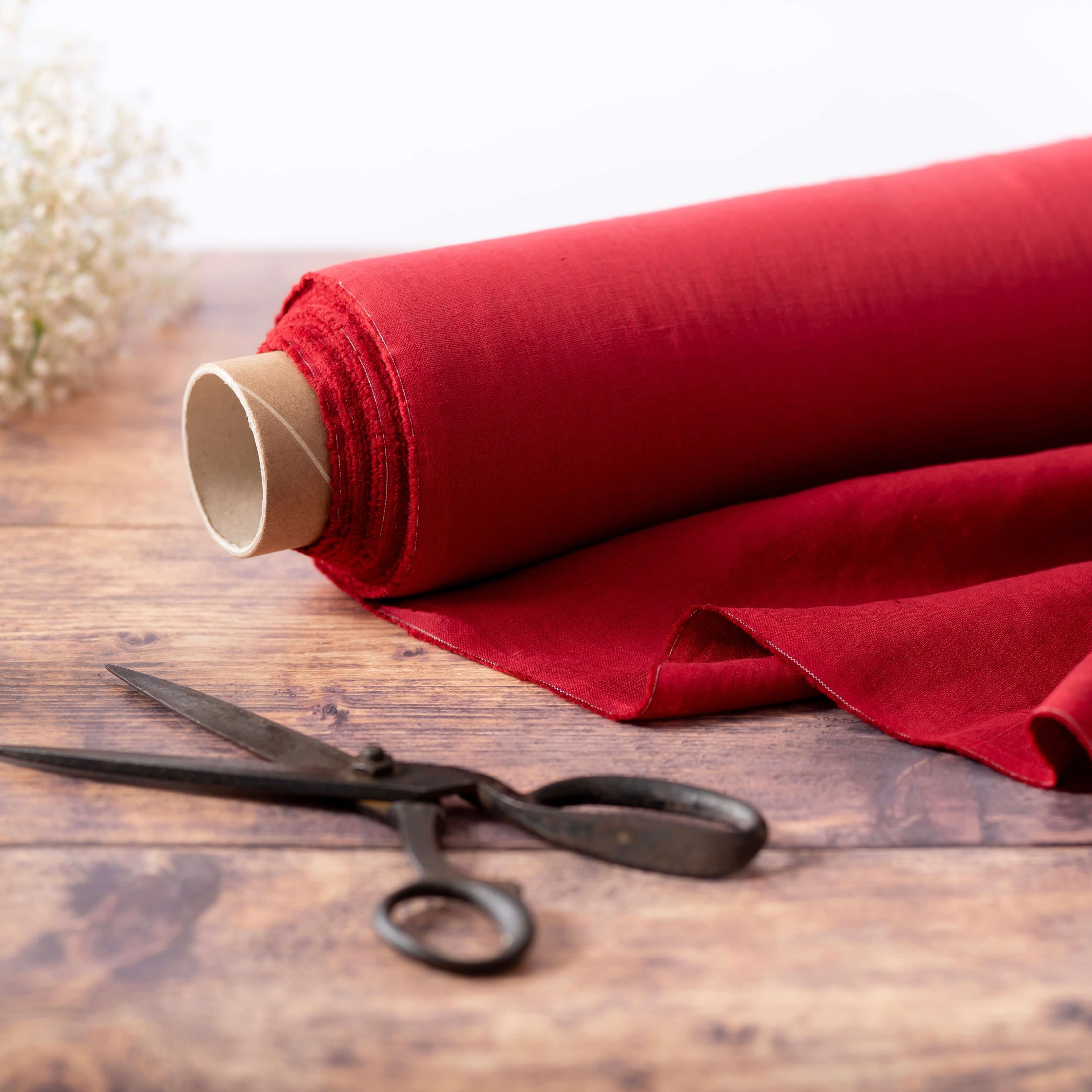Roll of linen fabric on wooden table with scissors